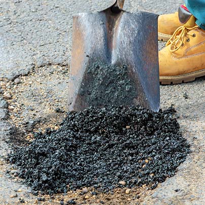 Man filling pothole asphalt